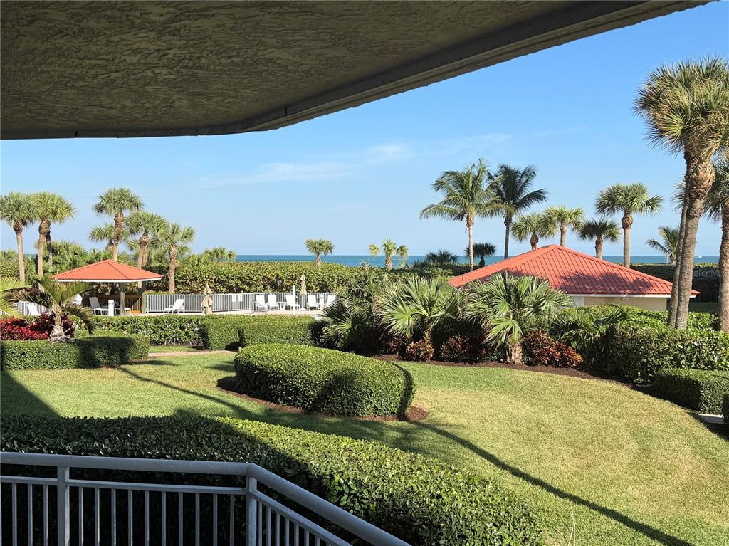 A view from a balcony overlooking a landscaped lawn, palm trees, and the ocean — 3880 N HIGHWAY A1A UNIT 104, HUTCHINSON ISLAND, FL