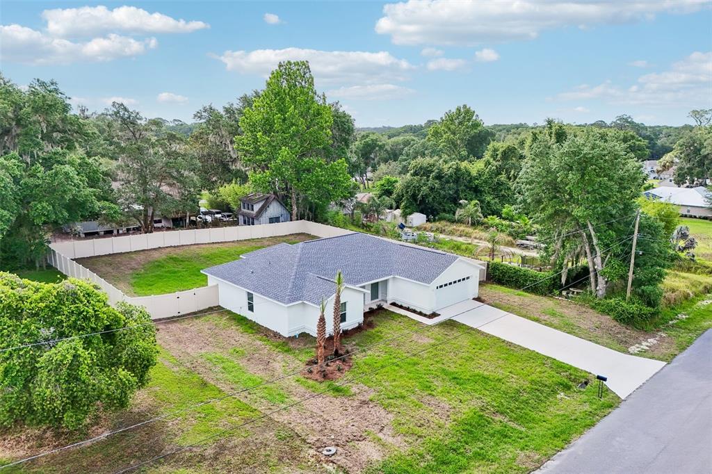 An aerial view shows a white, single-story house with a gray roof and fenced yard — 11591 MOCKINGBIRD DRIVE, DUNNELLON, FL
