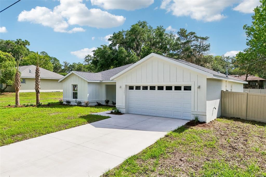 A white, single-story house with a two-car garage and a concrete driveway — 11591 MOCKINGBIRD DRIVE, DUNNELLON, FL