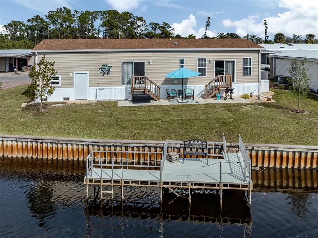 A tan manufactured home with a backyard, patio, and private dock on a canal — 106 ISLAND POINT ROAD, NORTH PORT, FL