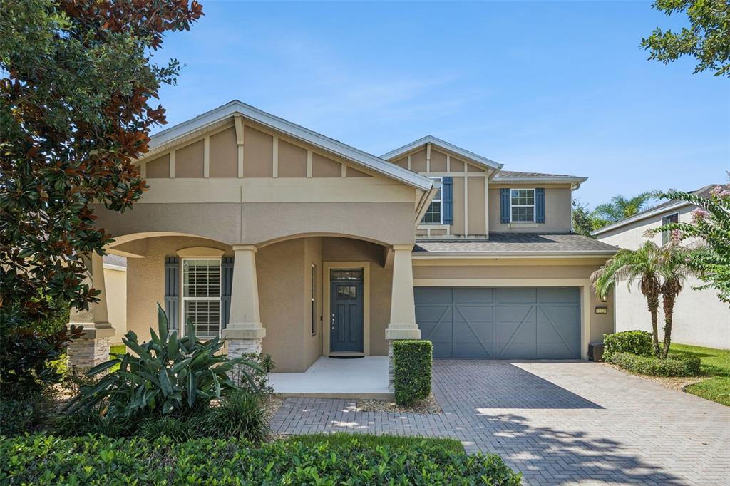 A two-story house with a beige stucco exterior, a gray garage door, and a brick driveway — 13328 OVERSTREET ROAD, WINDERMERE, FL