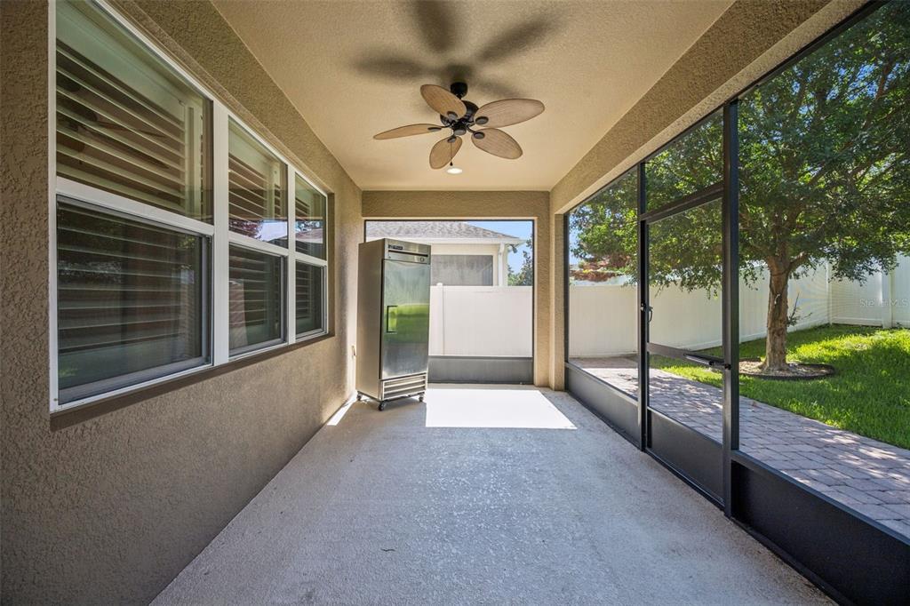 A covered patio with a ceiling fan, concrete flooring, and a large metal refrigerator — 13328 OVERSTREET ROAD, WINDERMERE, FL