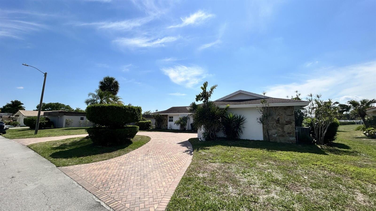 A single-story house with a stone facade and a paved driveway under a blue sky — 5728 S Bayberry Lane, Tamarac FL 33319, TAMARAC, FL