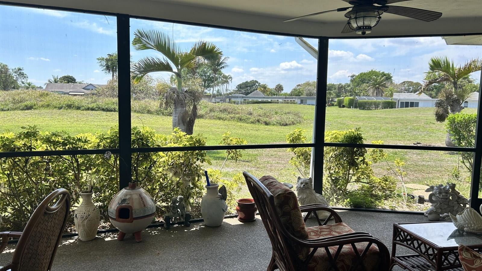 A screened-in porch features wicker furniture, decorative pottery, and a view of a grassy yard — 5728 S Bayberry Lane, Tamarac FL 33319, TAMARAC, FL