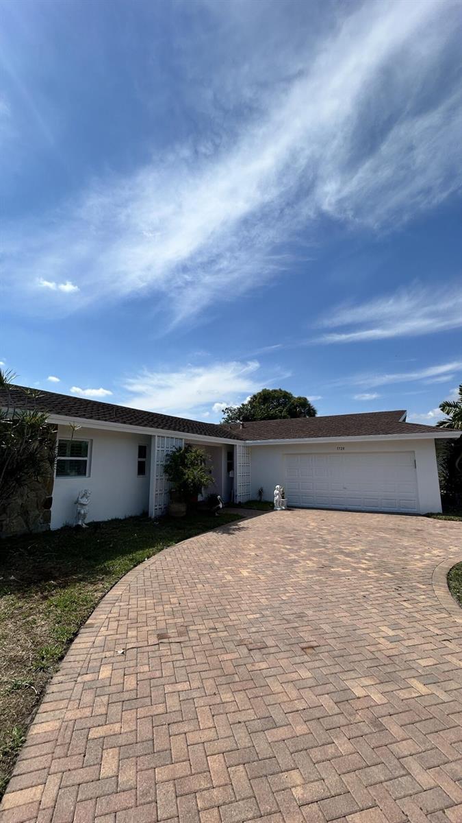 A single-story house with a white exterior, a brown shingled roof, and a brick driveway — 5728 S Bayberry Lane, Tamarac FL 33319, TAMARAC, FL