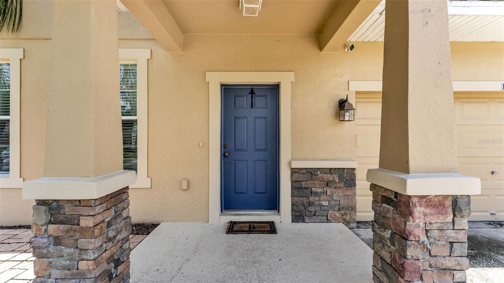 The front entrance features a blue door, stone-accented pillars, and a concrete porch — 2746 WALDEN WOODS DRIVE, PLANT CITY, FL