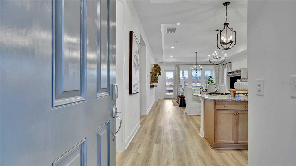 A view from a blue front door into a bright open-concept home with wood flooring — 1533 TREGAN AVENUE, DELAND, FL