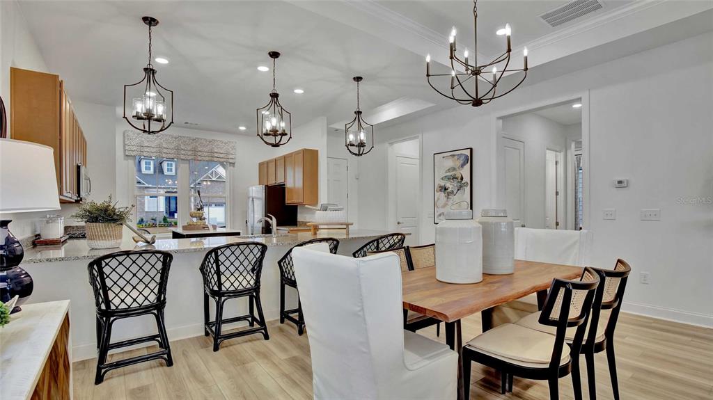 A kitchen with an island and bar stools opens into a dining area with chairs — 1533 TREGAN AVENUE, DELAND, FL