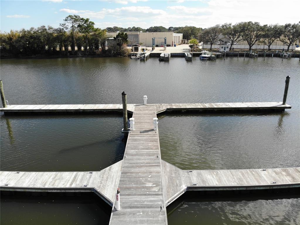 An aerial view shows a wooden T-shaped boat dock extending into a calm waterway — 1 MARINA DEL PALMA UNIT B21, PALM COAST, FL