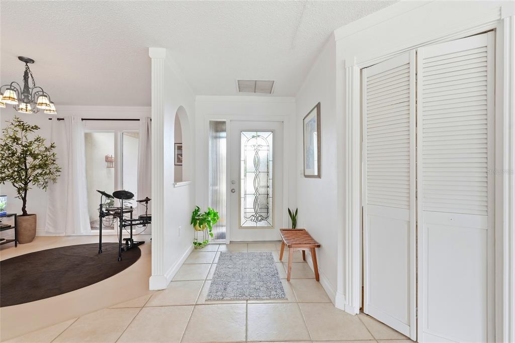An entryway features tiled floors, a white front door with glass, and a louvered closet — 3927 COUNTRY VIEW LANE, SARASOTA, FL