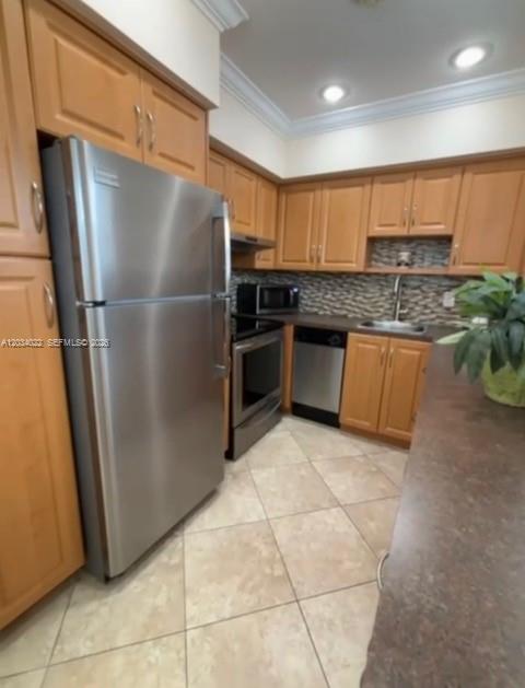 A kitchen features light wood cabinets, stainless steel appliances, a tiled floor, and a backsplash — 500 Layne Blvd # 20, Hallandale Beach FL 33009, HALLANDALE BEACH, FL