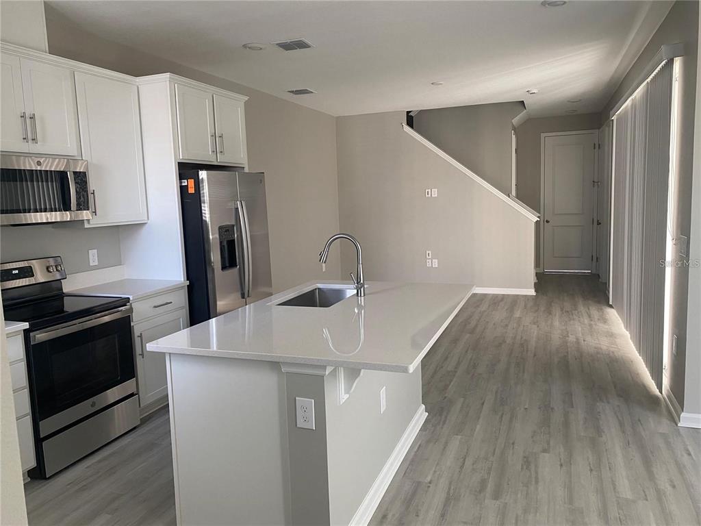 A kitchen with white cabinets, stainless steel appliances, and a central island with a sink — 1457 AXEL GRAESON AVENUE, KISSIMMEE, FL