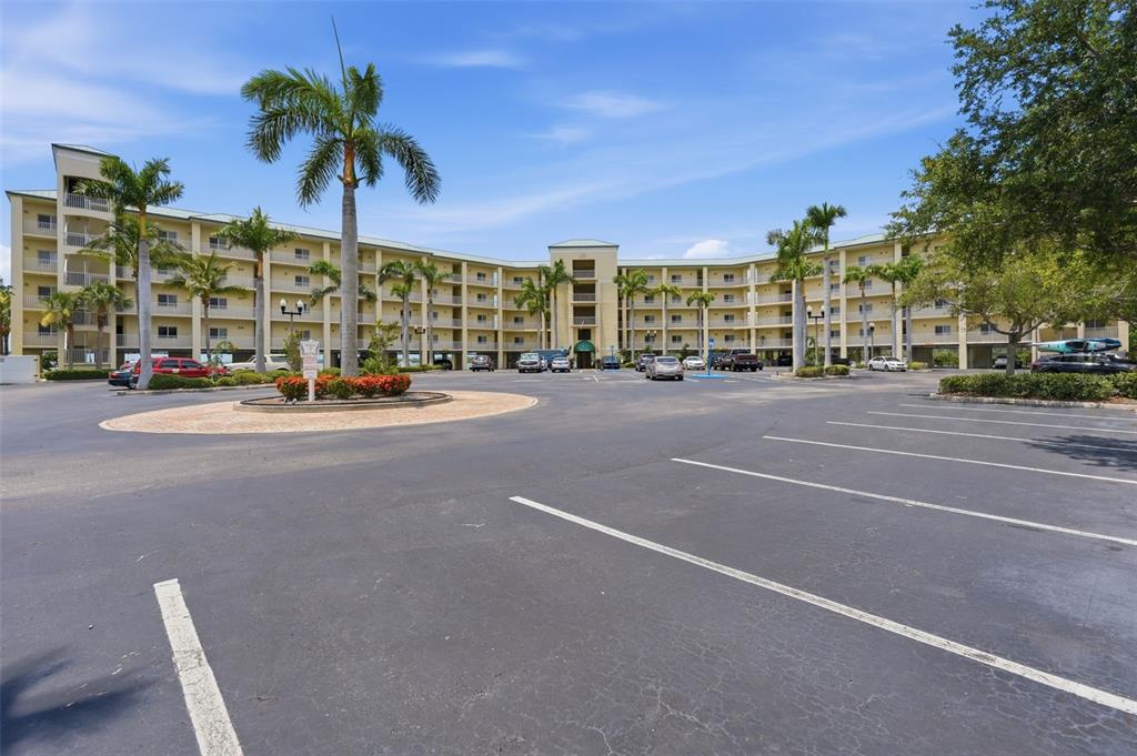 A multi-story apartment building with a large parking lot and palm trees in front — 8800 BAY PINES BOULEVARD UNIT 216, ST PETERSBURG, FL