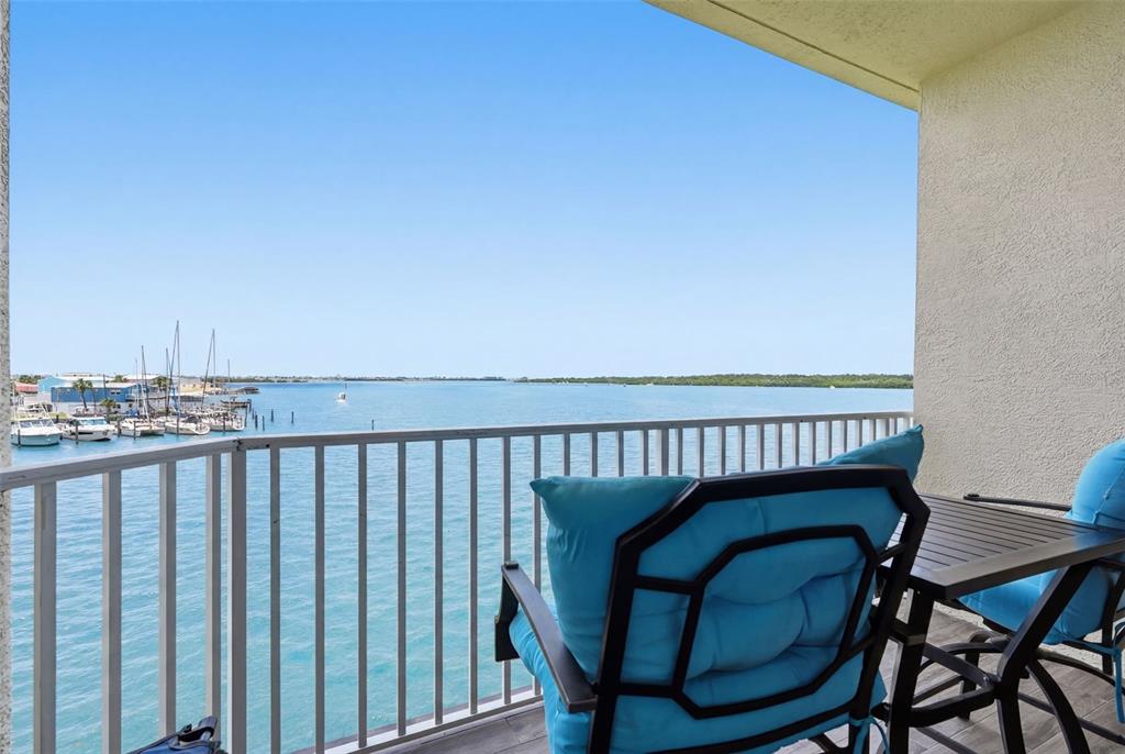 A balcony with blue cushioned chairs overlooks a marina and a wide body of water — 8800 BAY PINES BOULEVARD UNIT 216, ST PETERSBURG, FL