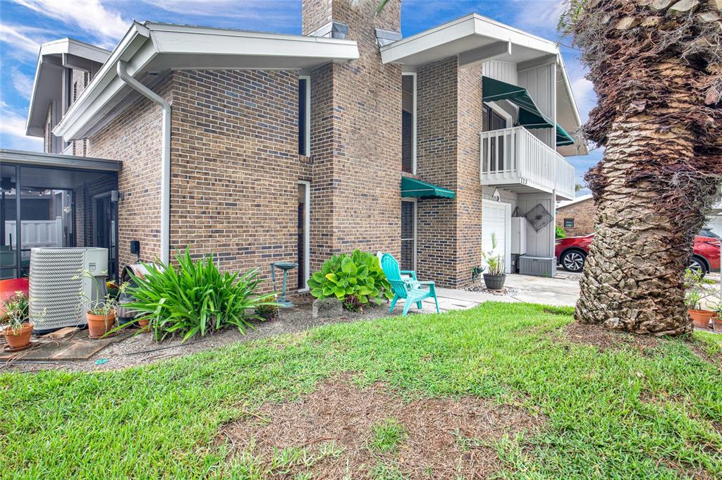 A two-story brick building features a balcony, green awnings, and a large palm tree — 113 LAGOON COURT, NEW SMYRNA BEACH, FL