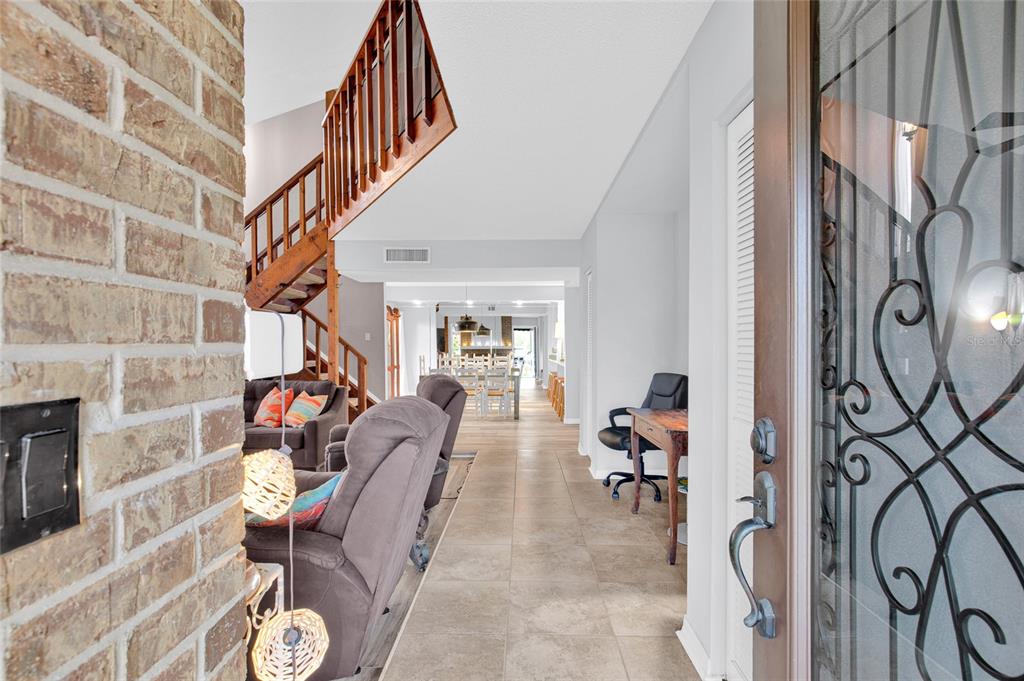 An entryway leads into a living room with a wooden staircase and tile flooring — 113 LAGOON COURT, NEW SMYRNA BEACH, FL