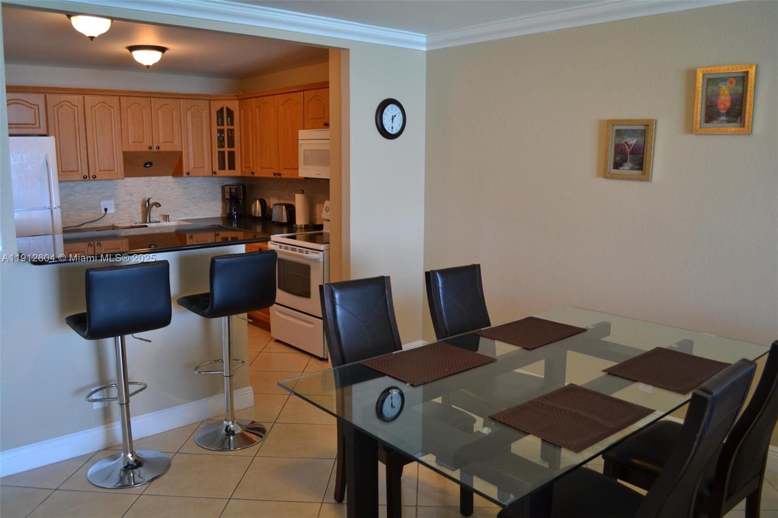 A dining area with a glass table and black chairs sits beside a kitchen — 2101 S Ocean Dr # 1702, Hollywood FL 33019, HOLLYWOOD, FL