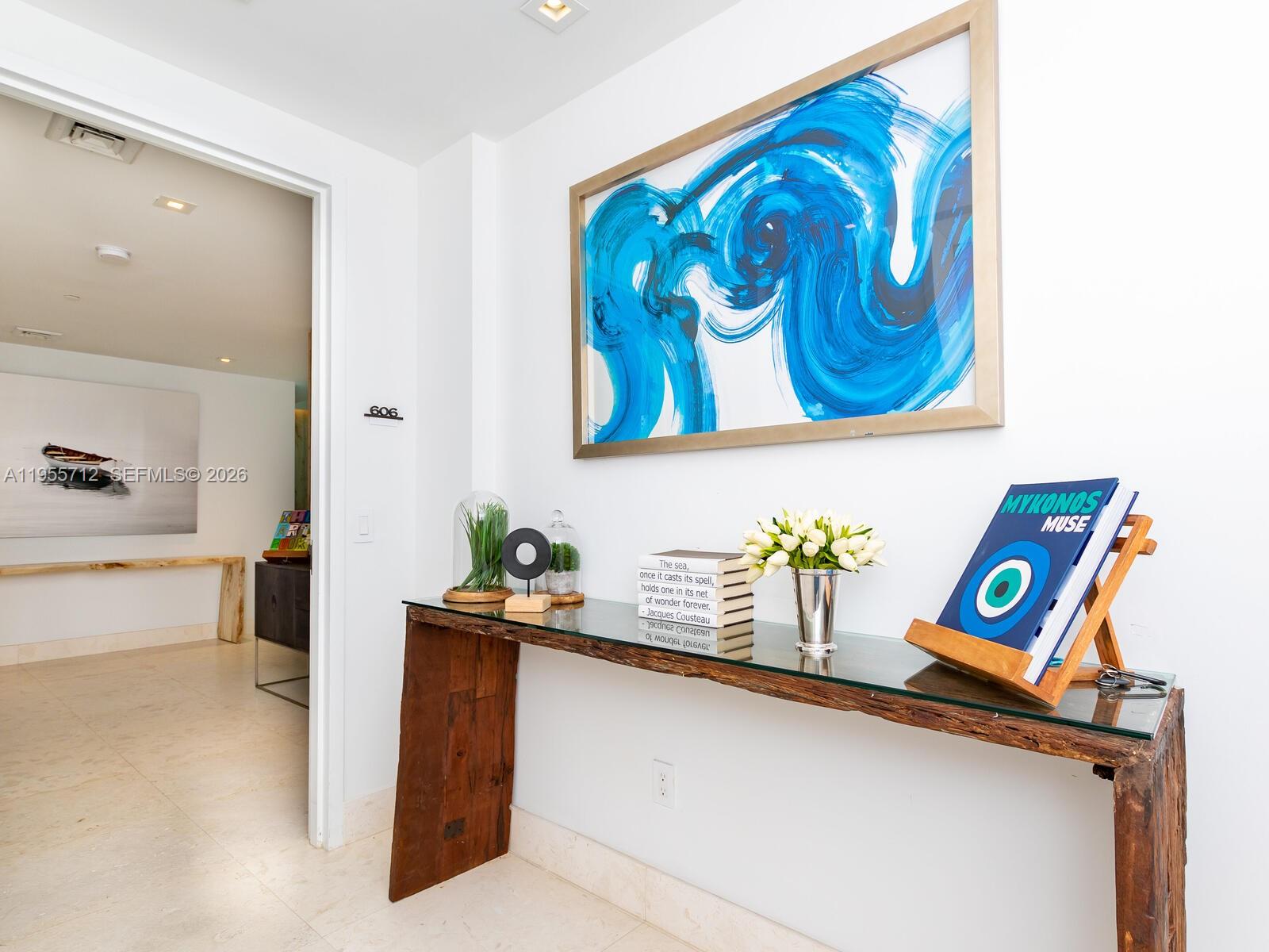 A console table with a glass top and wooden base sits in a white hallway — 360 Ocean Dr # 606S, Key Biscayne FL 33149, KEY BISCAYNE, FL