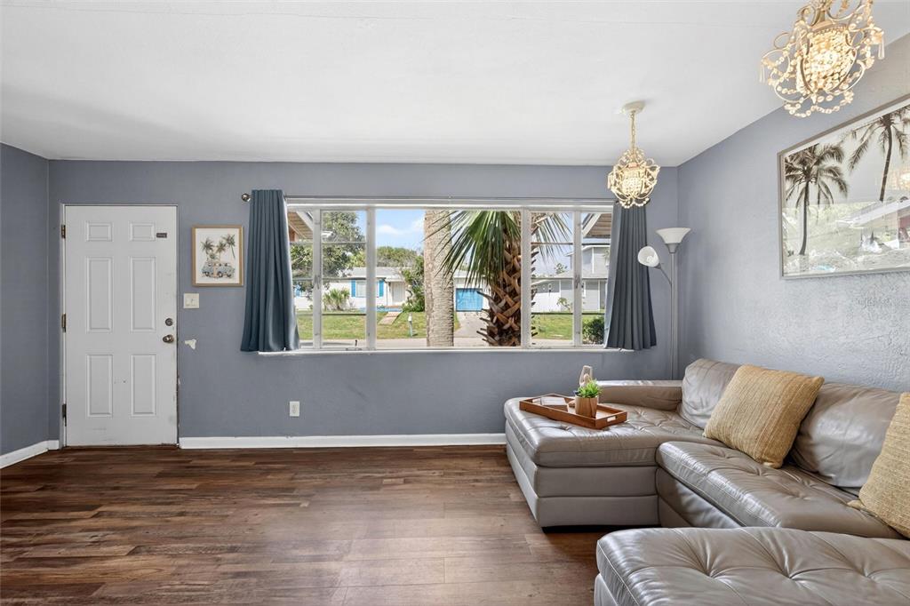 A living room features gray walls, wood-look flooring, a sectional sofa, and a large window — 109 CLAIRE TERRACE, DAYTONA BEACH, FL
