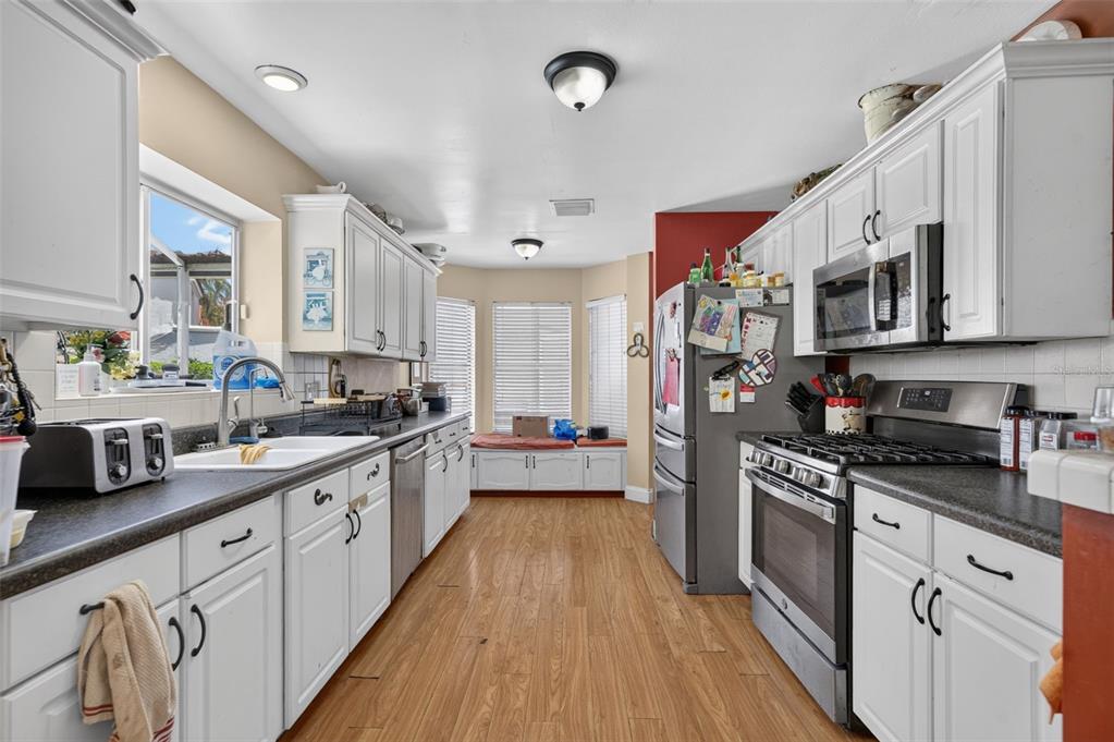 A kitchen with white cabinets, stainless steel appliances, dark countertops, and a windowed breakfast nook — 2650 ALBION AVENUE, ORLANDO, FL