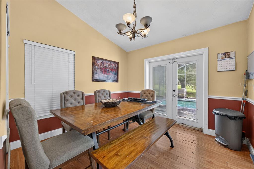 A dining room features a wooden table, a bench, upholstered chairs, and a sliding glass door — 2650 ALBION AVENUE, ORLANDO, FL