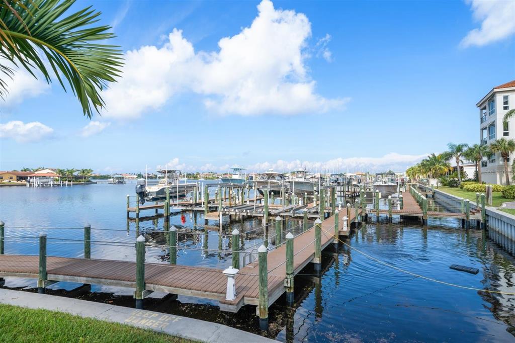 A wooden dock with multiple boat slips extends into a canal lined with residential buildings — 1030 BELLASOL WAY UNIT 3201, APOLLO BEACH, FL