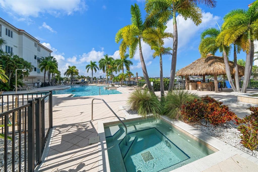 A hot tub sits in the foreground of a pool deck with palm trees and cabana — 1030 BELLASOL WAY UNIT 3201, APOLLO BEACH, FL