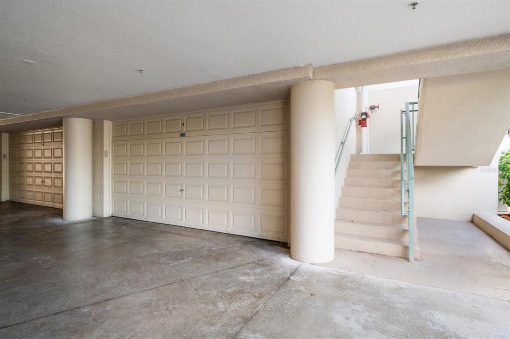 A covered parking area with two garage doors and a concrete staircase leading upward — 1030 BELLASOL WAY UNIT 3201, APOLLO BEACH, FL