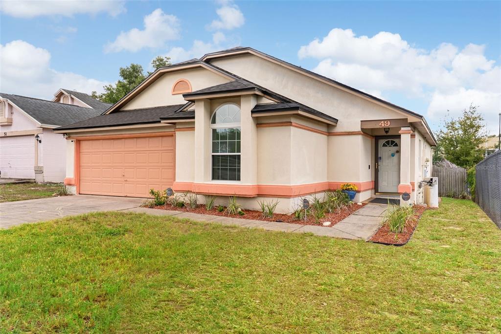 A single-story house with a peach-colored garage door, stucco exterior, and a front walkway — 49 GRAND JUNCTION BOULEVARD, ORLANDO, FL