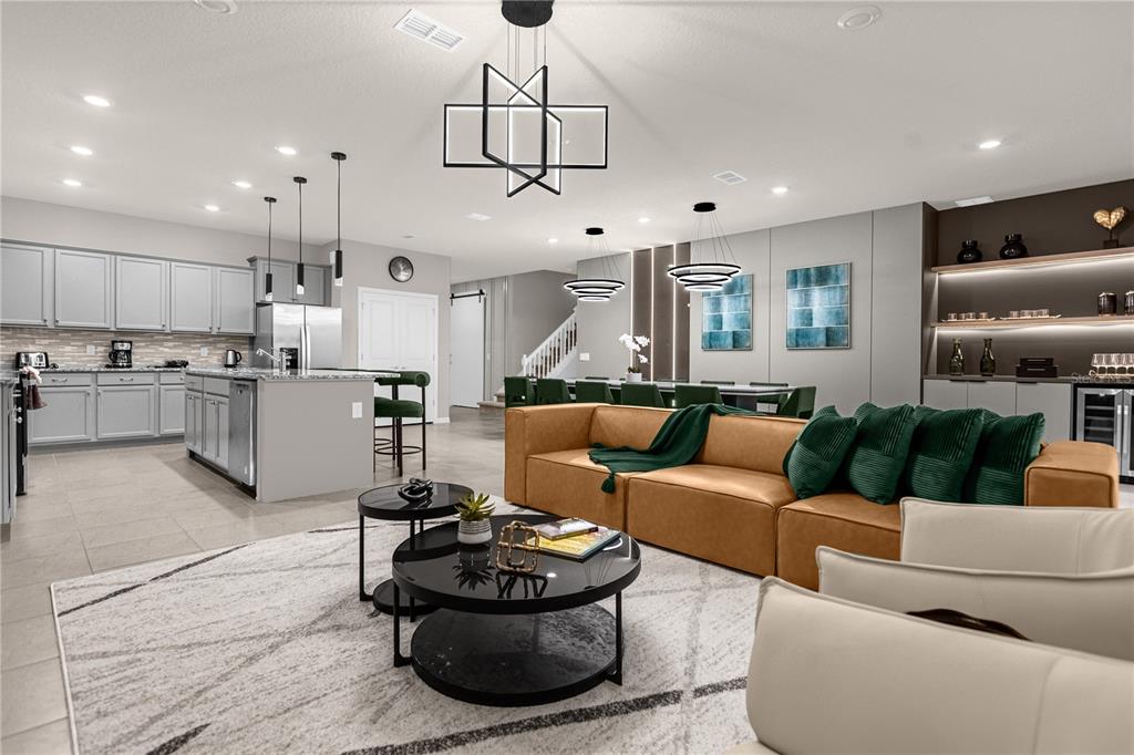 An open-concept living room and kitchen featuring a tan sofa, island, and modern light fixtures — 3048 MAHALO DRIVE, DAVENPORT, FL