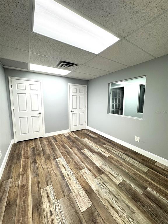 An office room features light gray walls, wood-look flooring, two white doors, and a window — 2401 W BAY DRIVE UNIT 414, LARGO, FL