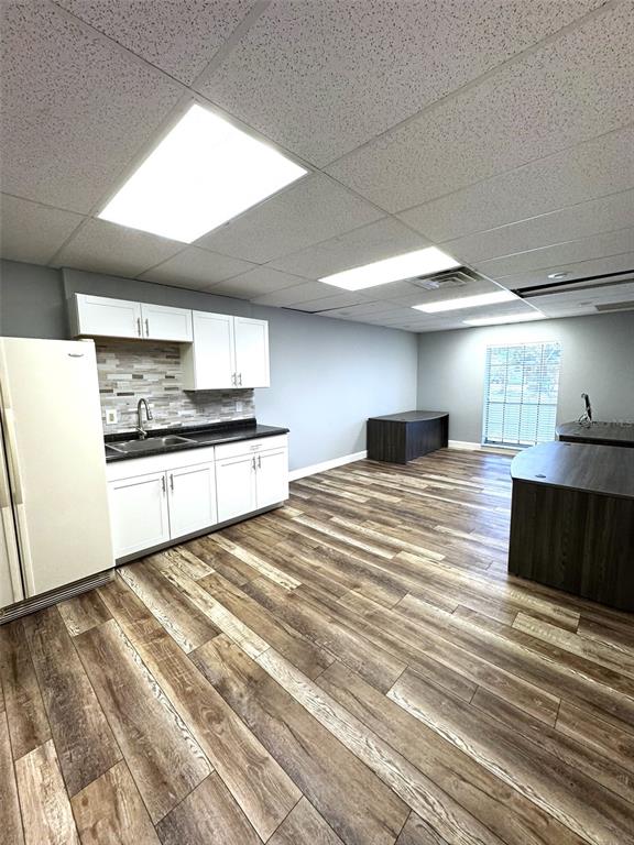 An office breakroom features white cabinets, a sink, wood-look flooring, and two dark desks — 2401 W BAY DRIVE UNIT 414, LARGO, FL