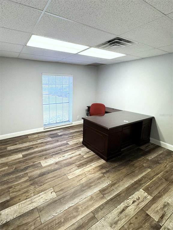 An office room features wood-look flooring, a dark wood desk, and a red chair — 2401 W BAY DRIVE UNIT 414, LARGO, FL