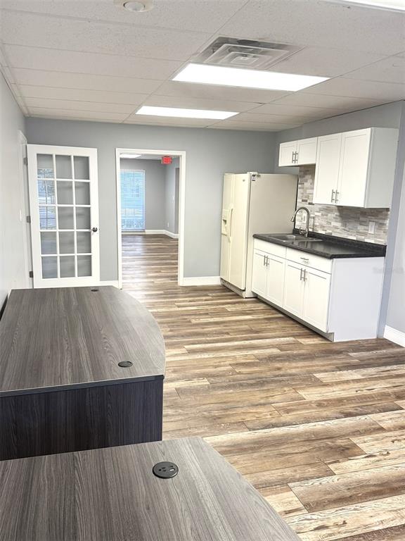 An office breakroom features white cabinets, a refrigerator, a sink, and wood-look flooring — 2401 W BAY DRIVE UNIT 414, LARGO, FL