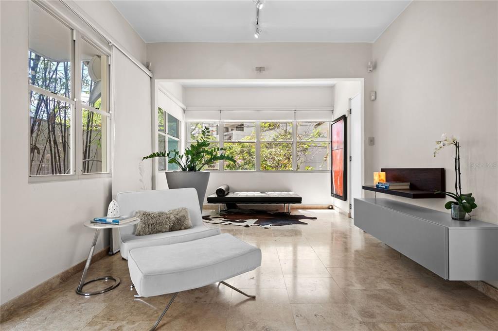 A bright living room features white tile floors, a white lounge chair, and large windows — 609 MIRAMAR AVENUE UNIT 102, SAN JUAN, PR