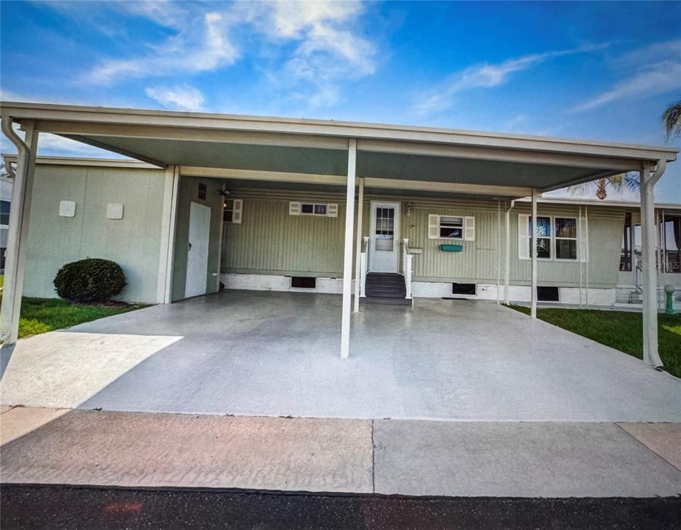 A light green mobile home features a concrete carport and a small front porch — 225 DIXIE LANE, TARPON SPRINGS, FL