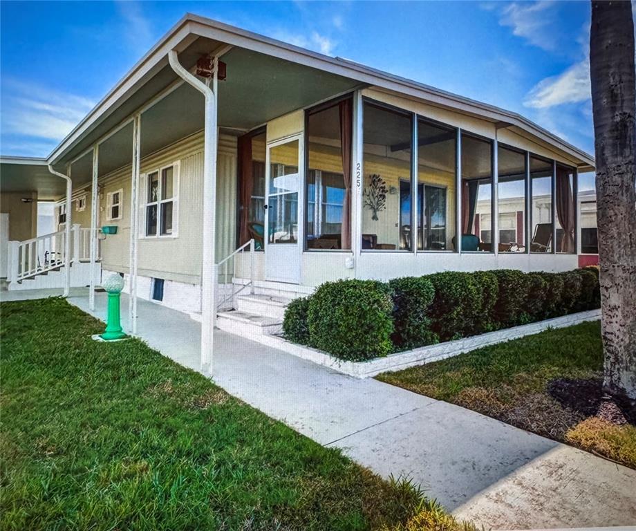 A single-story mobile home with a screened-in porch, white siding, and a concrete walkway — 225 DIXIE LANE, TARPON SPRINGS, FL
