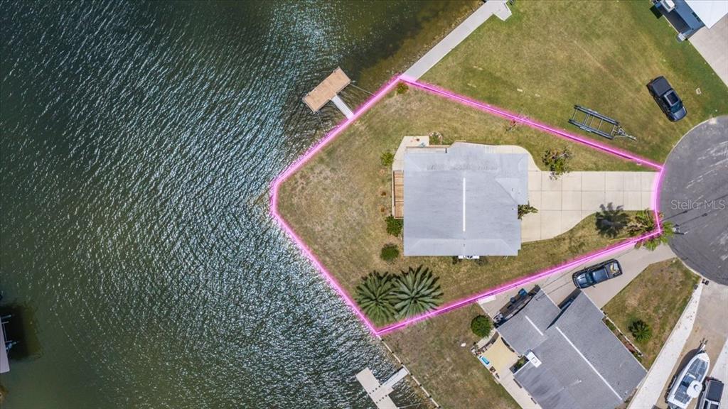 An aerial view shows a yellow waterfront house on a corner lot with two docks — 4365 4TH ISLE DRIVE, HERNANDO BEACH, FL