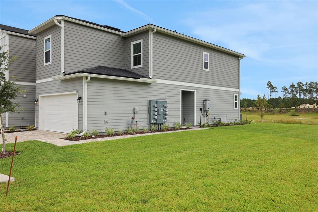 The exterior of a gray two-story townhouse features a white garage door and electrical meters — 155 WOOD BREEZE WAY, ST AUGUSTINE, FL