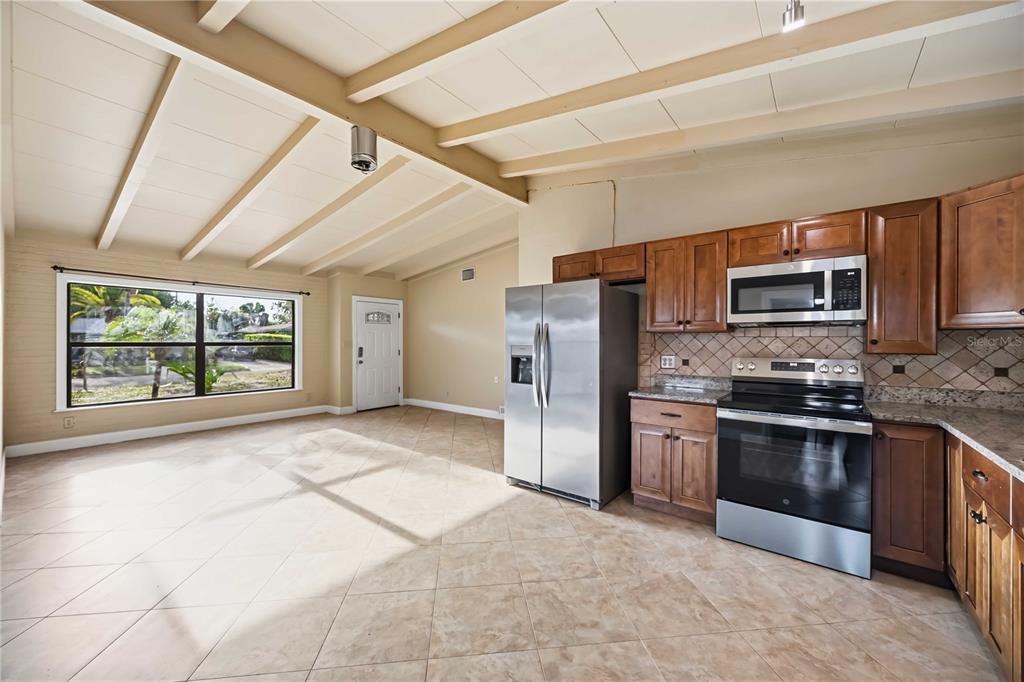 A kitchen with wood cabinets, stainless steel appliances, and tile flooring under a vaulted ceiling — 2715 INGOT PLACE, SARASOTA, FL