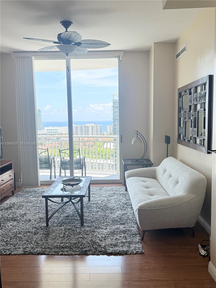 A living room features a white sofa, a glass coffee table, and a balcony view — 1755 E Hallandale Beach Blvd # 2505E, Hallandale Beach FL 33009, HALLANDALE BEACH, FL