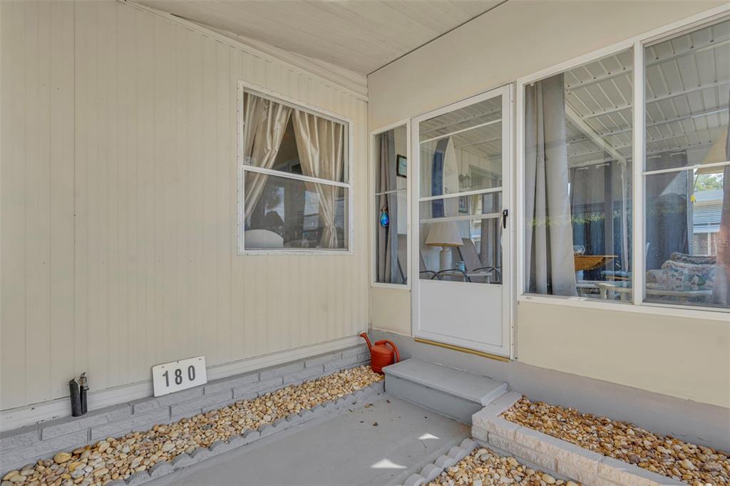 The exterior of a mobile home features a covered porch with gravel landscaping and siding — 180 PARADISE N, LEESBURG, FL
