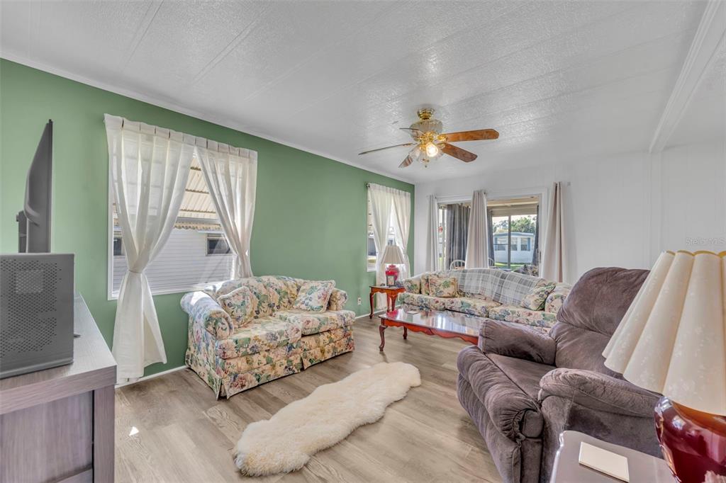A living room features a green accent wall, floral sofas, and a ceiling fan — 180 PARADISE N, LEESBURG, FL