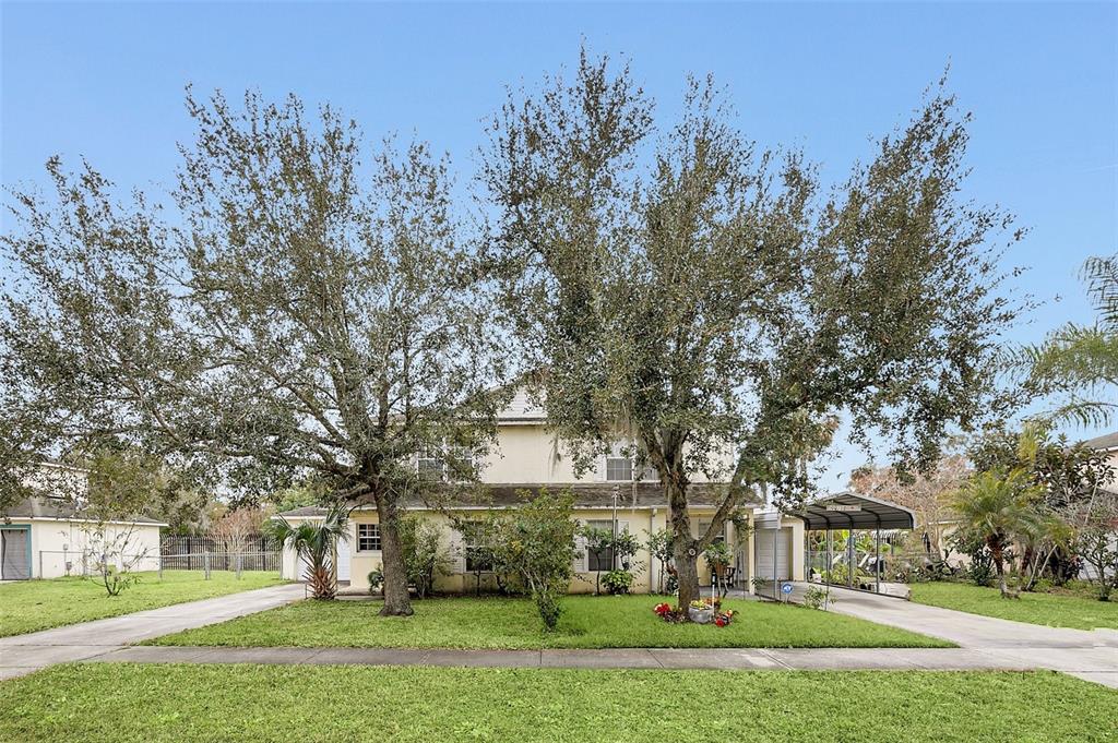 A two-story house with a light-colored exterior, two large trees, and two driveways — 1209 W 6TH STREET, SANFORD, FL