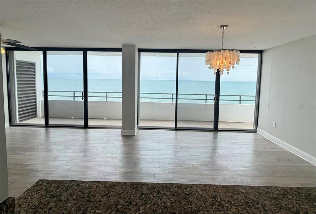 An open living area features light wood-look tile floors, a chandelier, and sliding glass doors — 1601 N CENTRAL AVENUE UNIT 1101, FLAGLER BEACH, FL