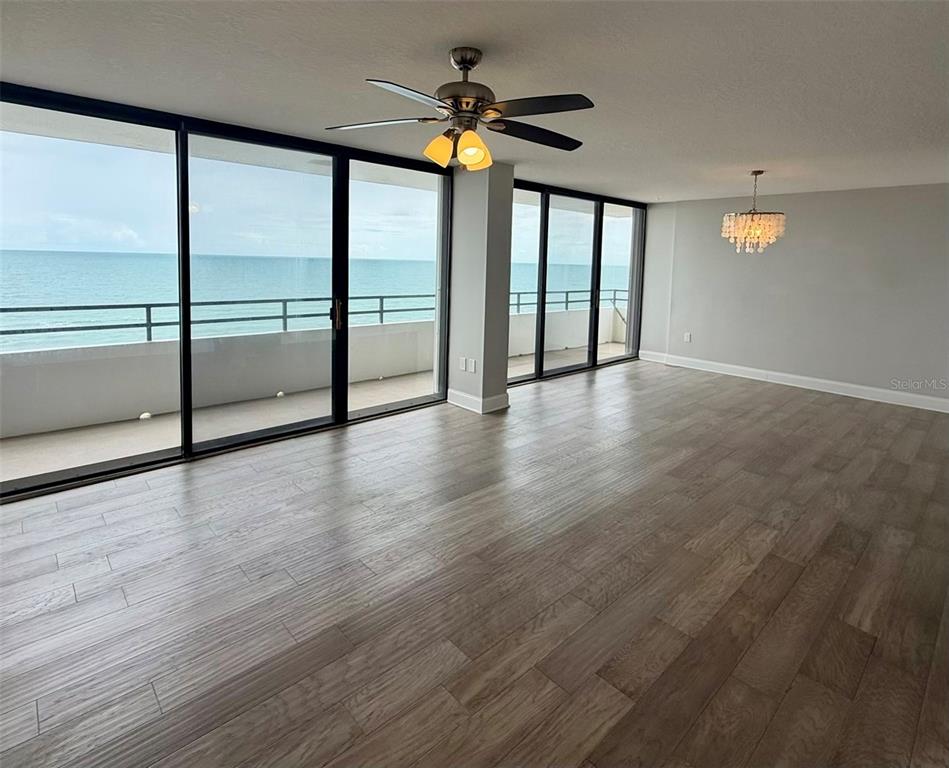 An empty room with wood-look flooring, a ceiling fan, a chandelier, and sliding glass doors — 1601 N CENTRAL AVENUE UNIT 1101, FLAGLER BEACH, FL