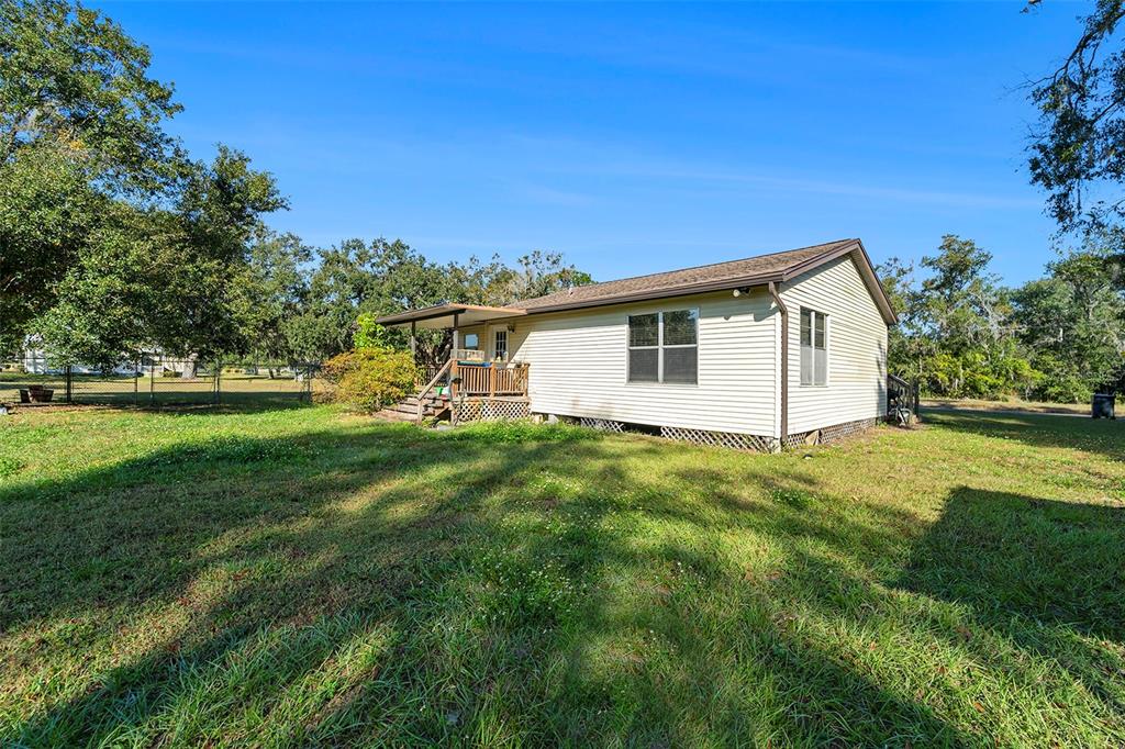 A single-story house with light-colored siding and a covered wooden porch sits on a lawn — 2215 WALLACE ROAD, LUTZ, FL