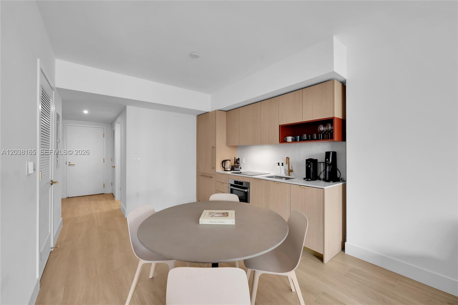 A modern kitchen features light wood cabinetry, a round dining table, and white walls — 90 NE 32nd # 406, Miami FL 33127, MIAMI, FL