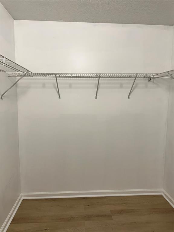 A walk-in closet features white walls, wood-look flooring, and a wire shelving system — 529 E Sheridan Street # 1081, Dania Beach FL 33004, DANIA BEACH, FL