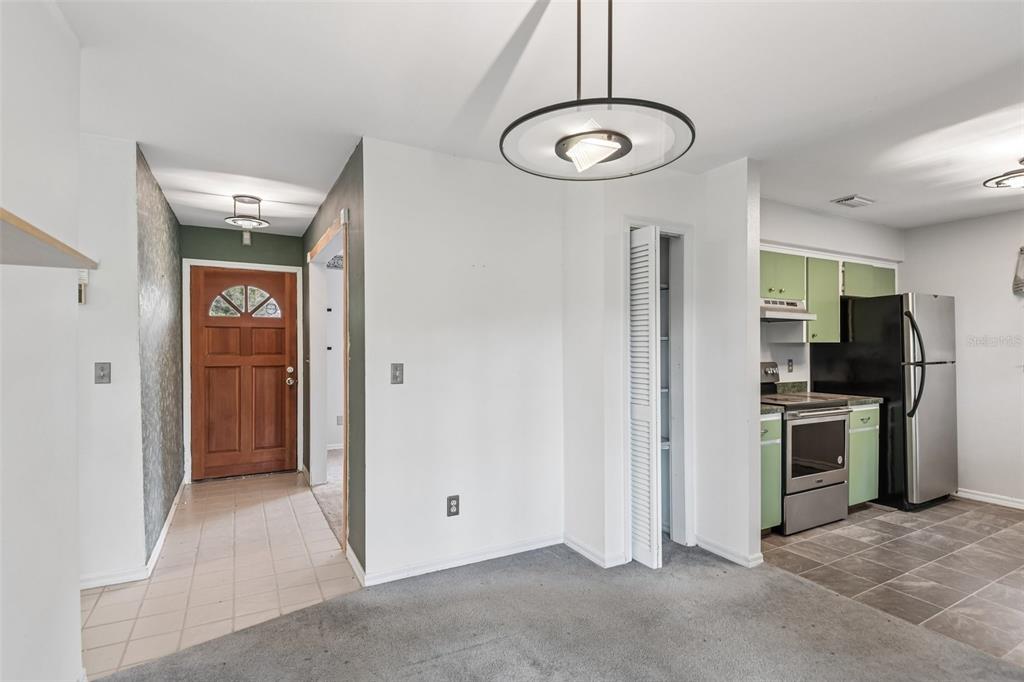 A dining area with gray carpet, a modern pendant light, and an adjacent kitchen — 18411 AUTUMN MIST DRIVE, LUTZ, FL